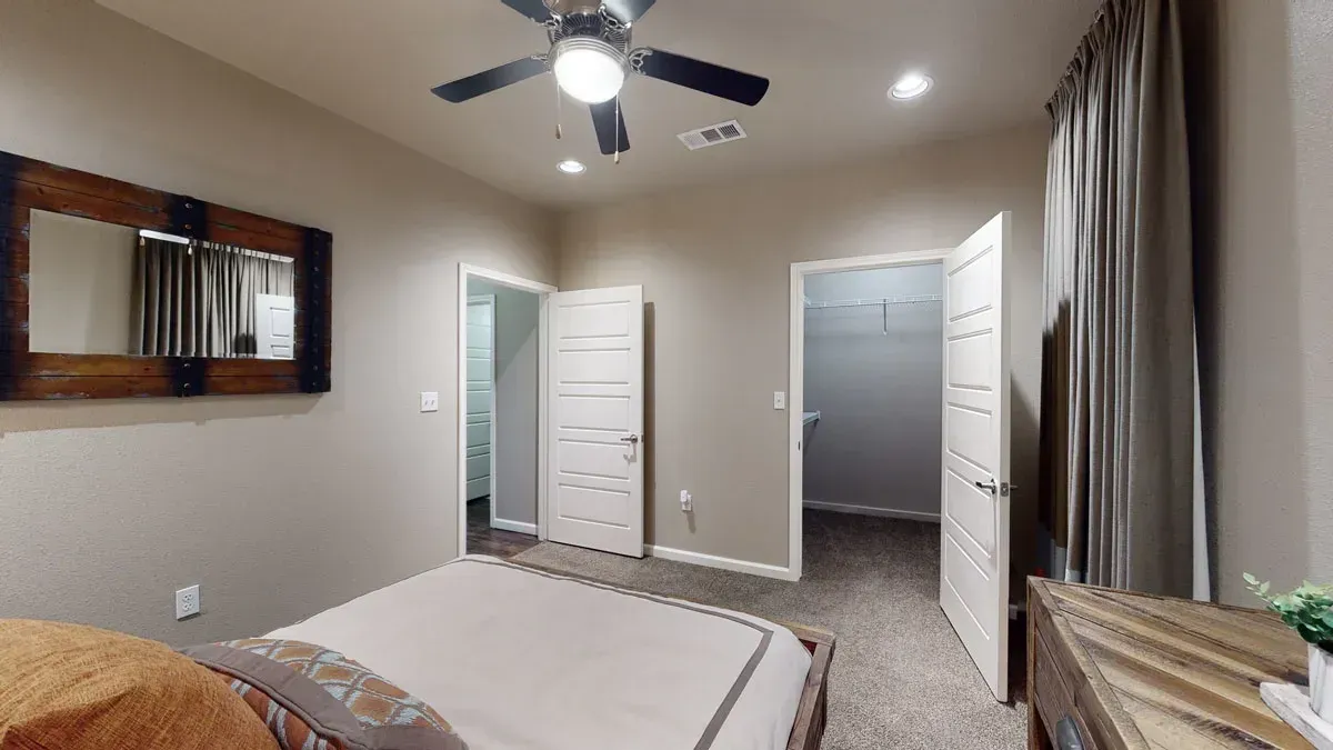 A bedroom with a bed , mirror and ceiling fan.