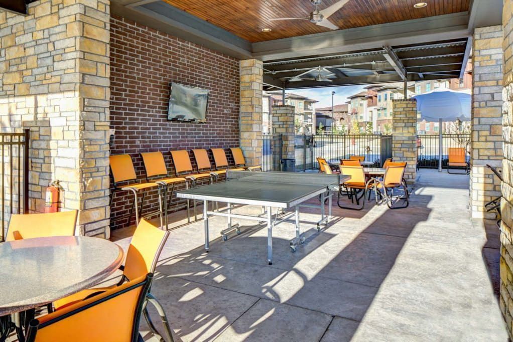 There is a ping pong table in the middle of the outdoor lounge.