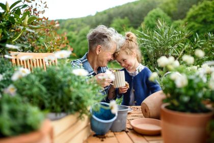 Two people smiling over mugs in a lush garden with potted plants and flowers Two people smiling over mugs in a lush garden with potted plants and flowers