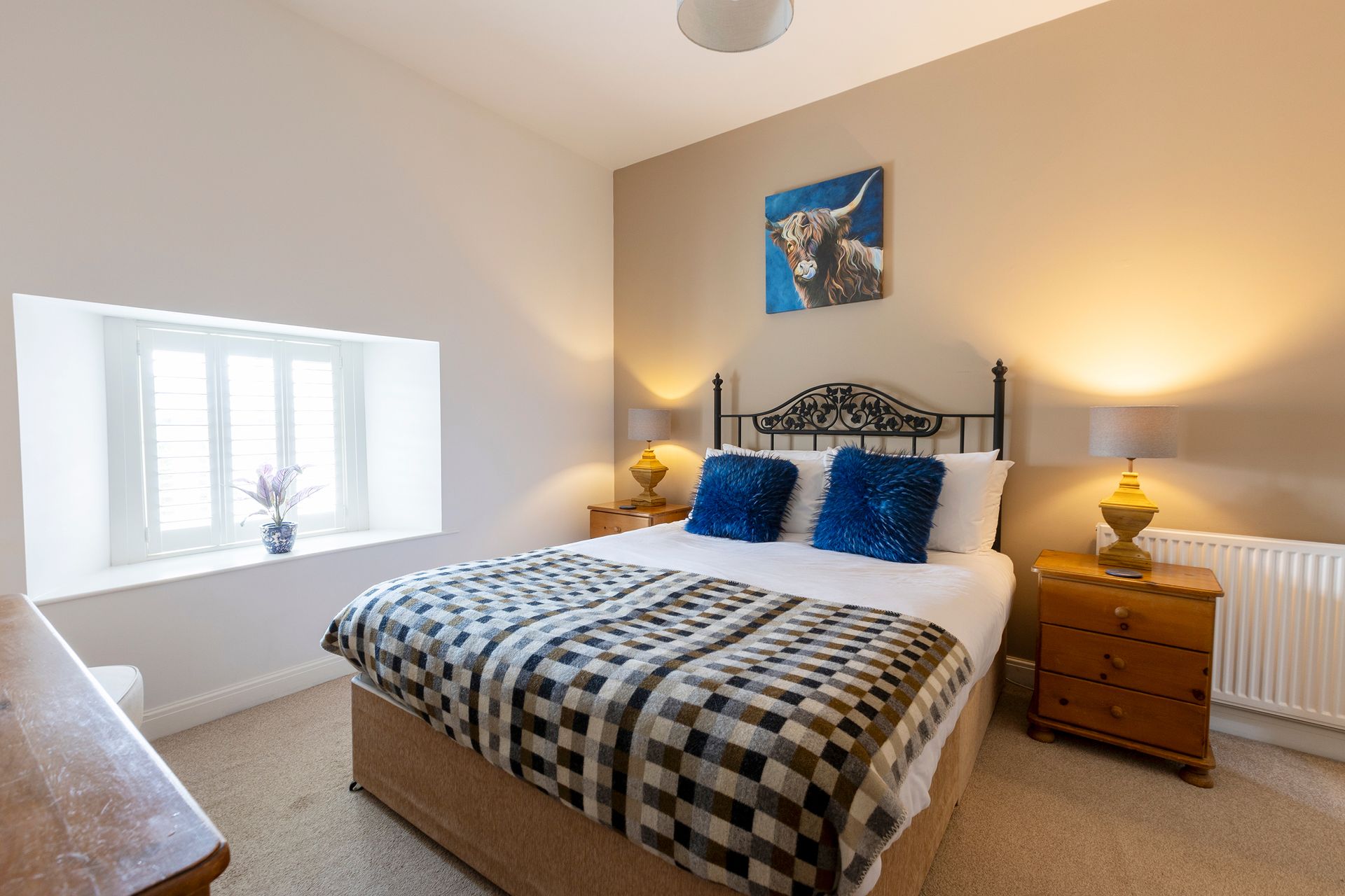 King bed wit blue fluffy cushions and cow painting