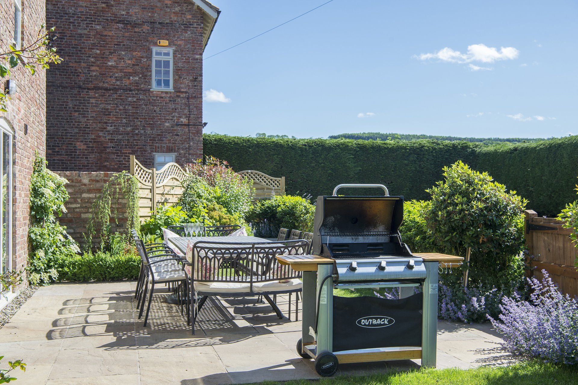 A grill is sitting on a patio next to a table and chairs.