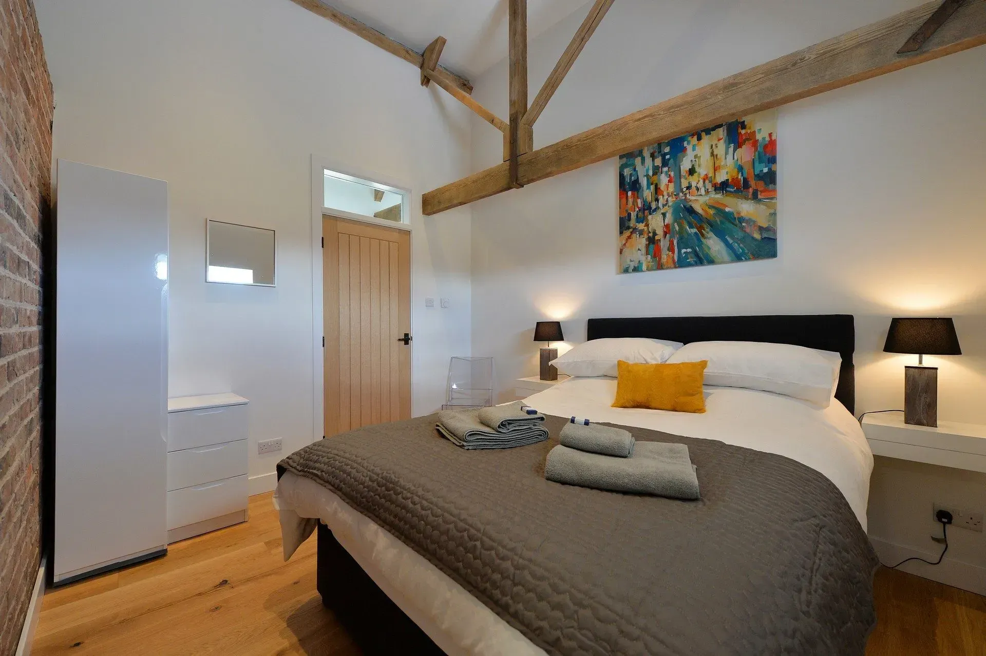 A bedroom with a large bed and a painting on the wall.