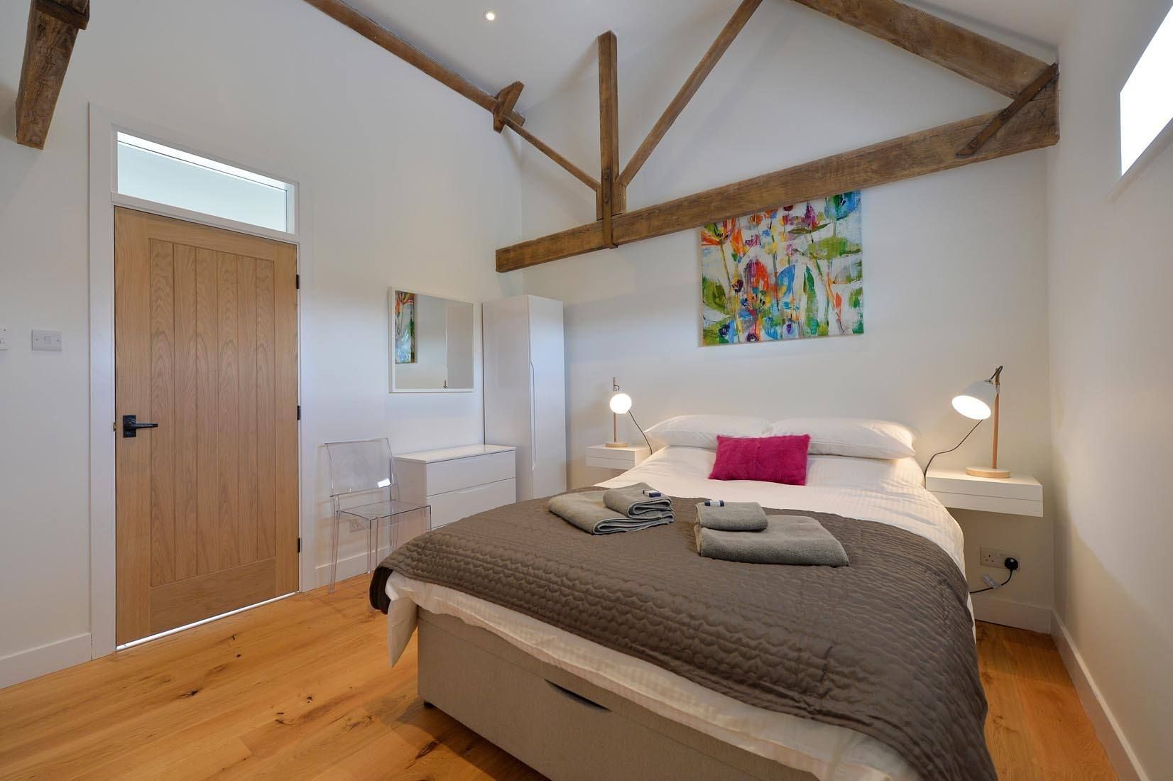 A bedroom with a king size bed , nightstand , chair and desk.