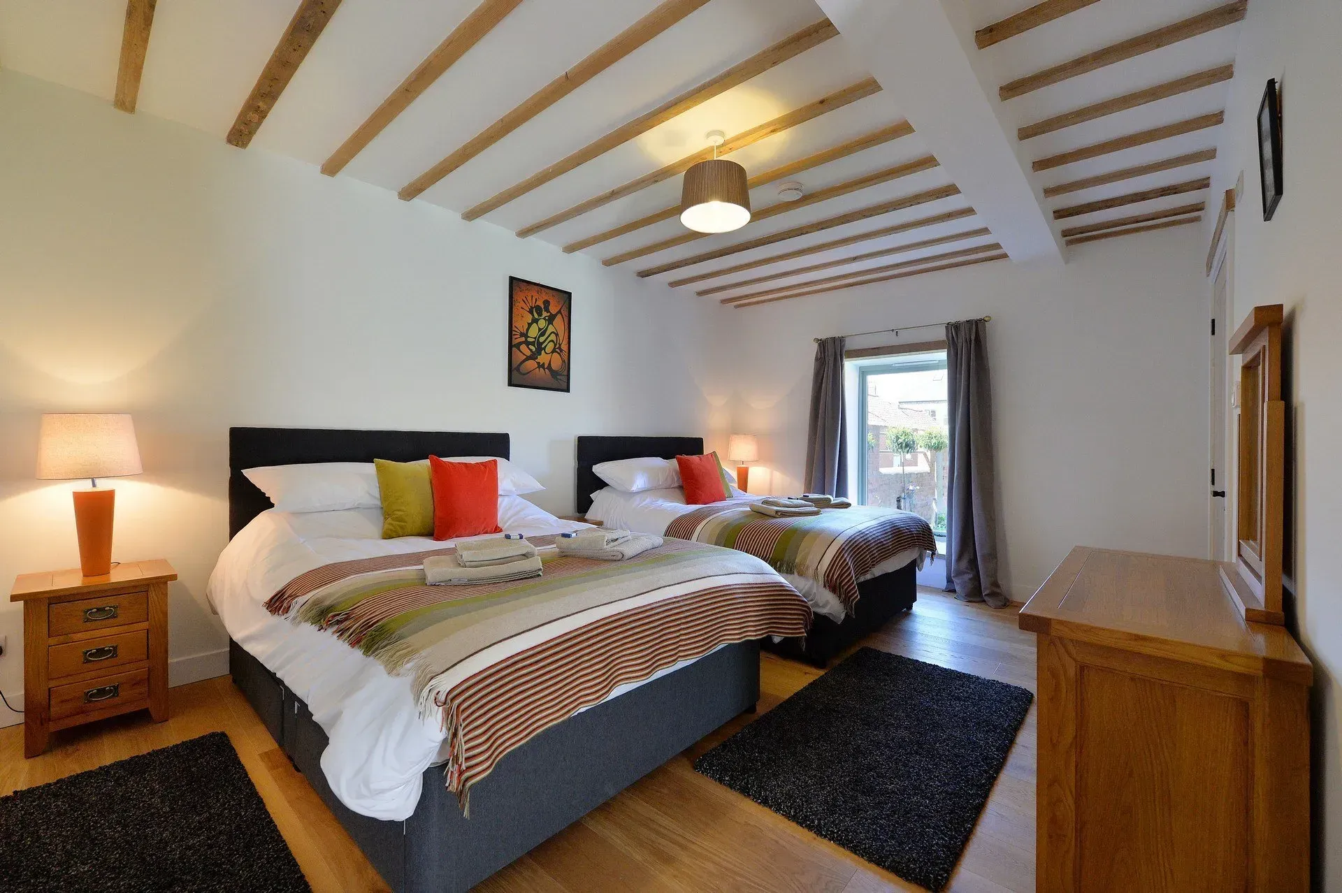 A bedroom with two beds , a dresser and a mirror.