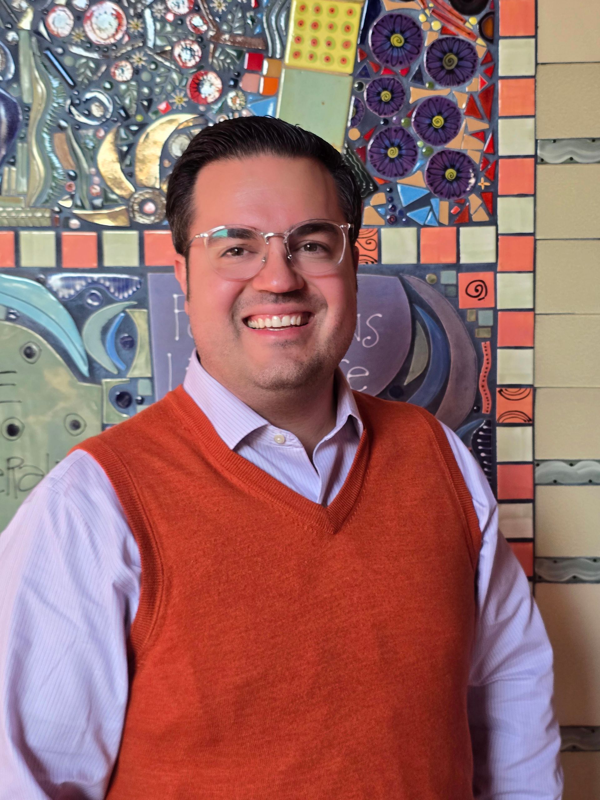 A man is smiling in front of a wall with signs on it