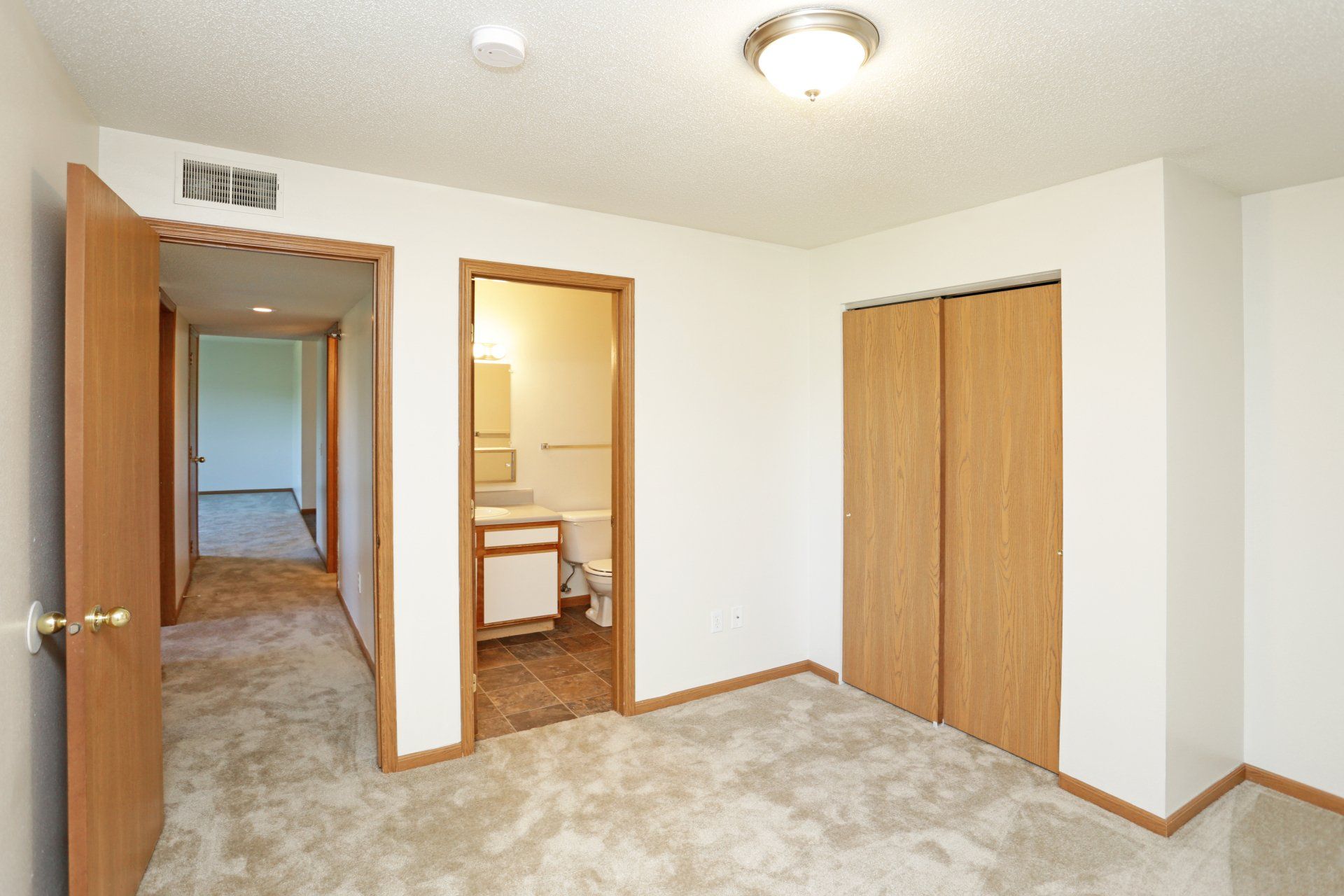 Bedroom view into bathroom with closet adjacent to doorway