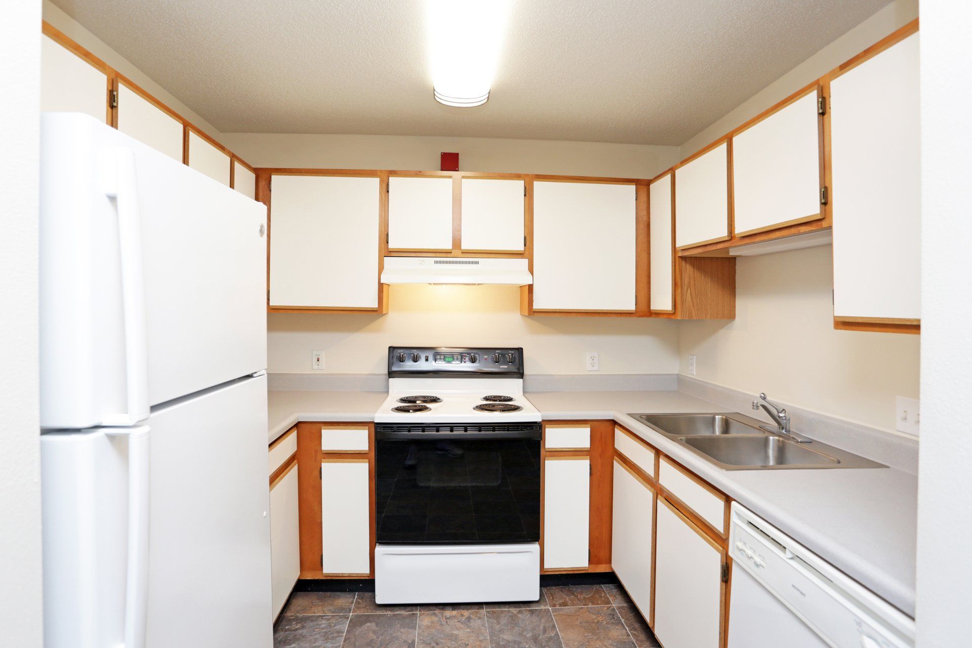 Kitchen view with white appliances and wood & white cabinetry