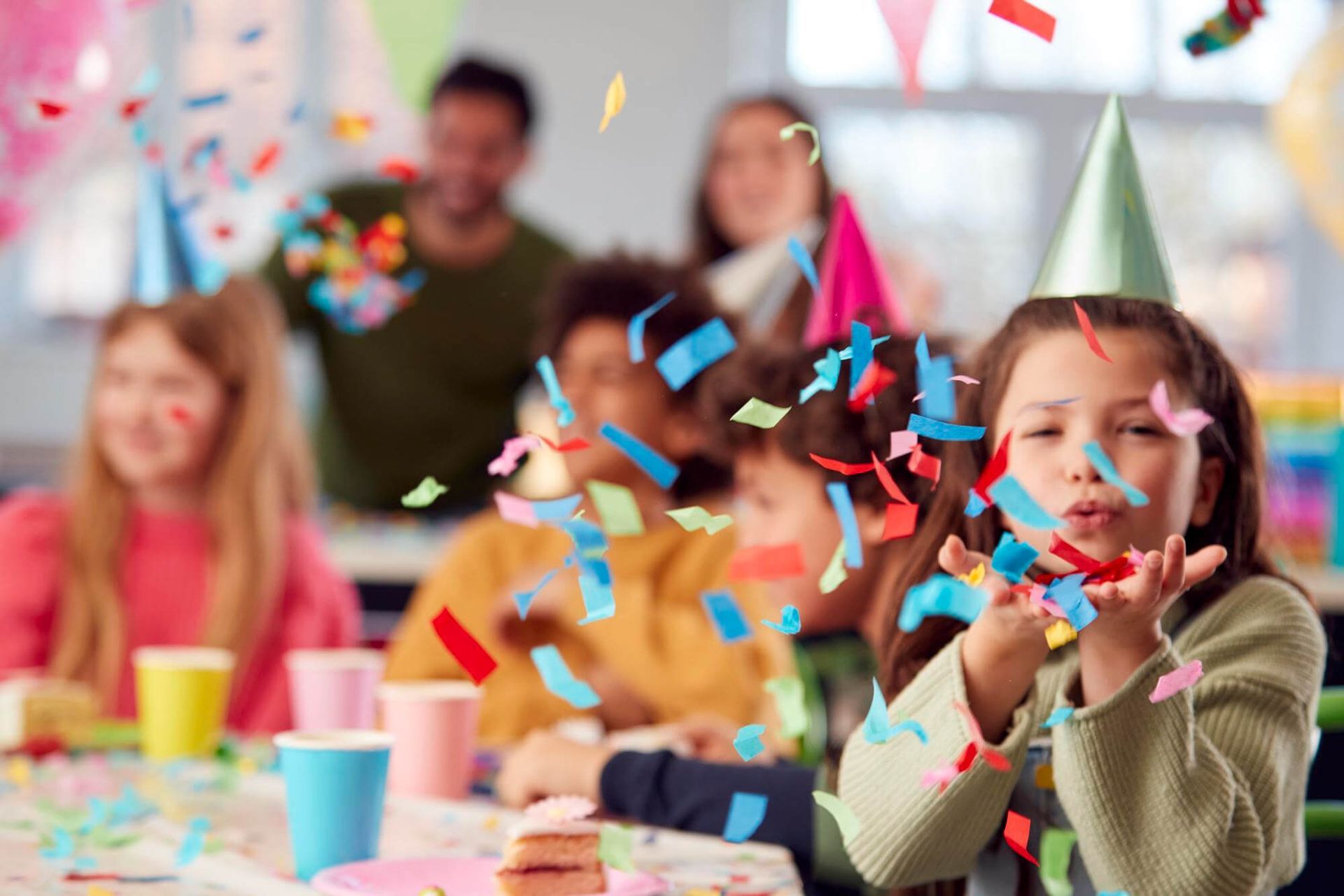 Una niña está soplando confeti en una fiesta de cumpleaños.