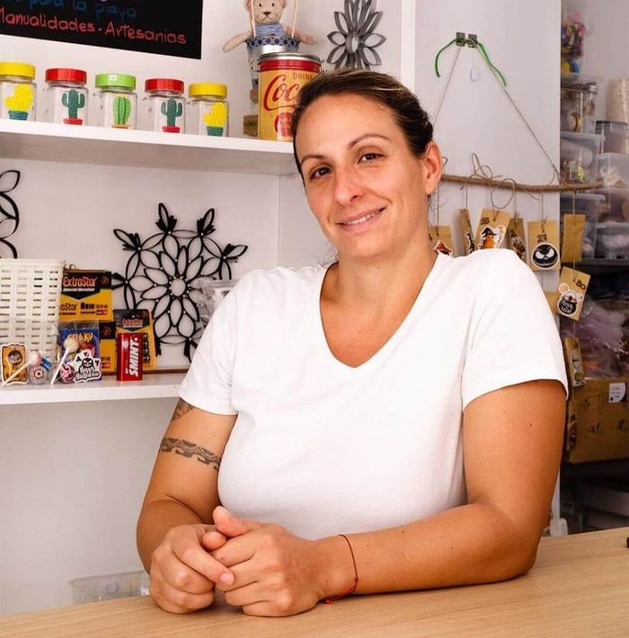 Una mujer con una camisa blanca está sentada en un mostrador frente a una lata de Coca Cola.