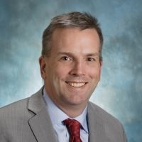 A man in a suit and tie is smiling for the camera.