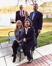 the Owens and  Kurz team are posing for a picture while sitting on a bench .