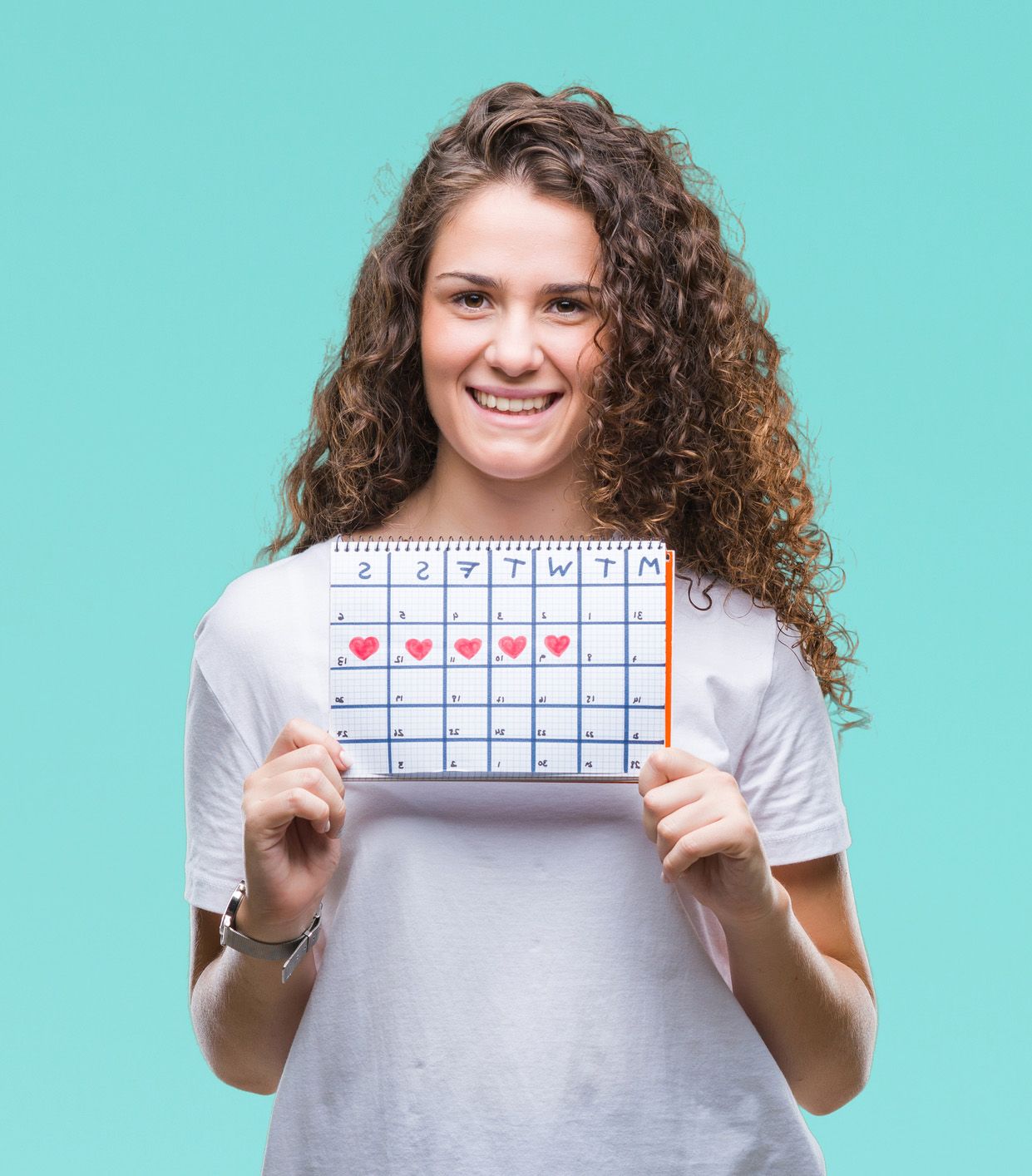 Woman holding calendar with heart symbols marking menstrual cycle days.