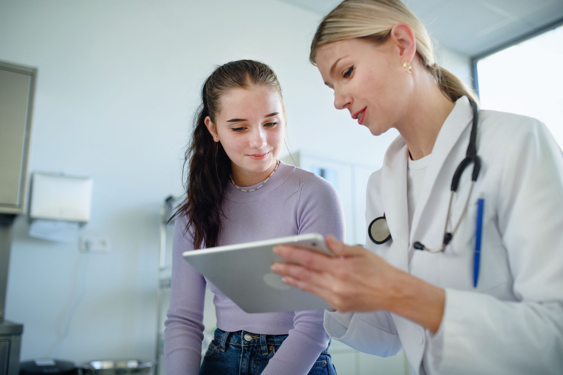 Doctor showing tablet to patient in examination room.