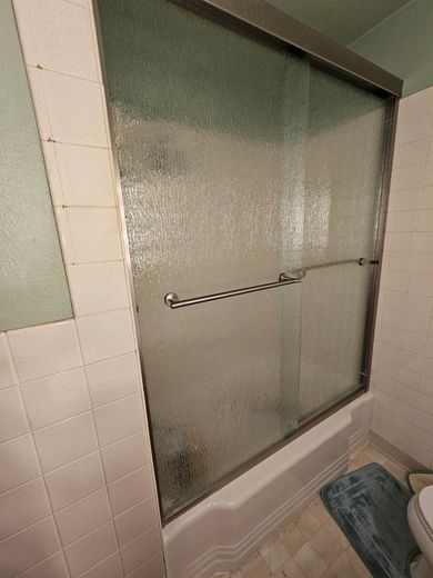 Frosted glass shower door with a silver handle in a tiled bathroom
