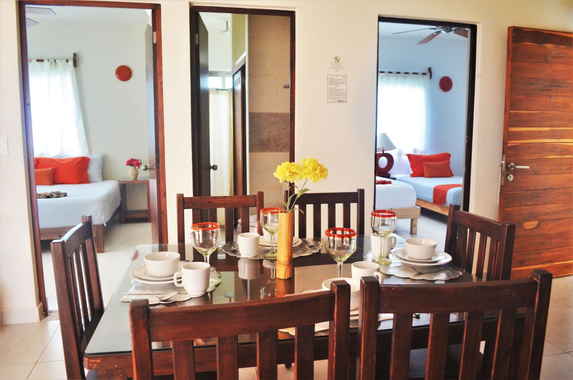 Comedor con mesa puesta para comer y puertas que conducen a los dormitorios.