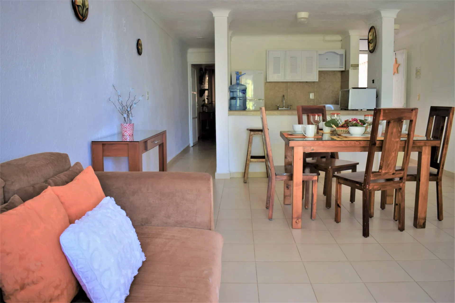 Sala de estar con sofá, mesa de comedor y cocina abierta.