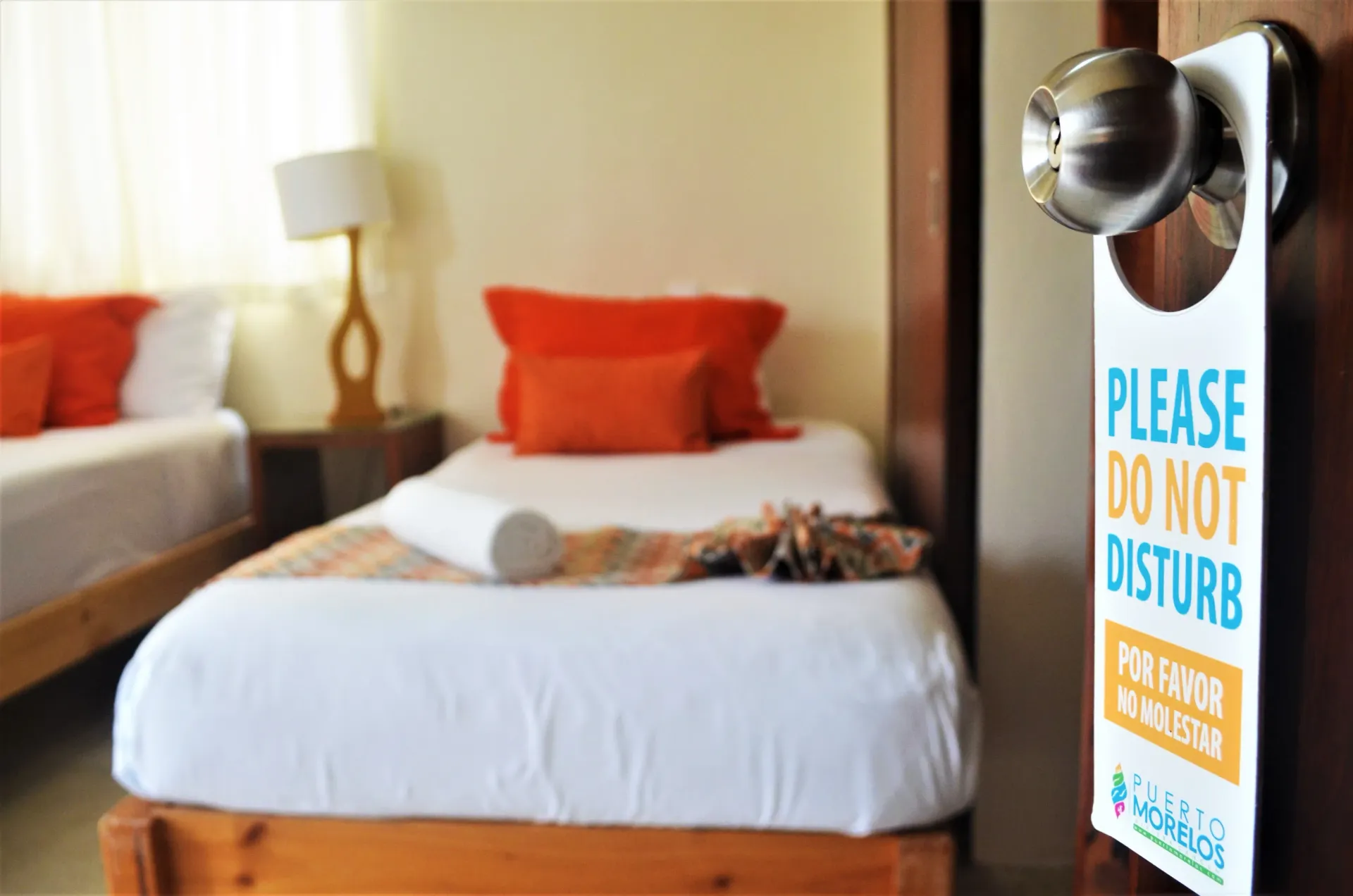 A hotel room with two beds, orange pillows, and a
