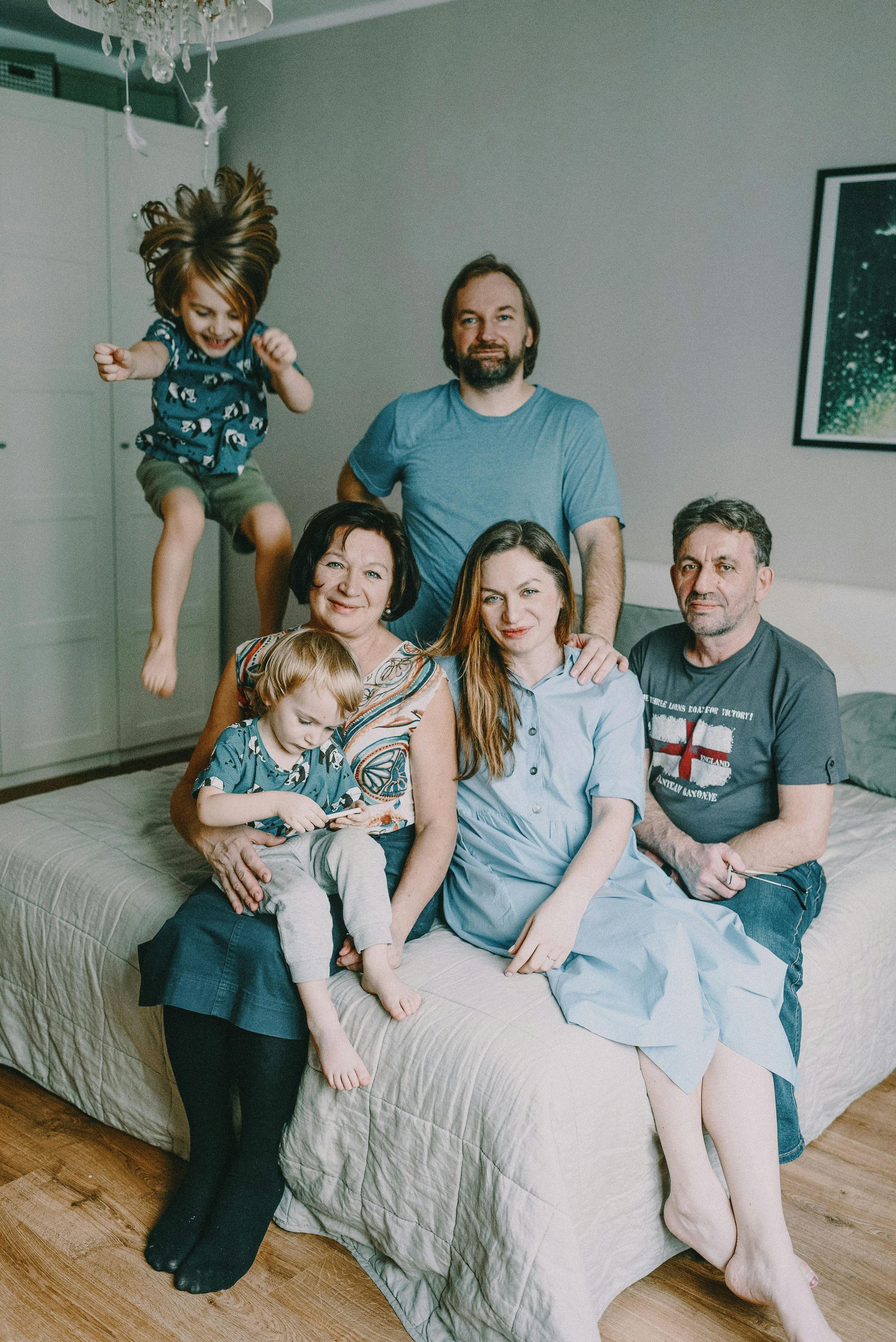 Family of six posing on a couch in a living room, with two children and two adults seated, one child standing behind.