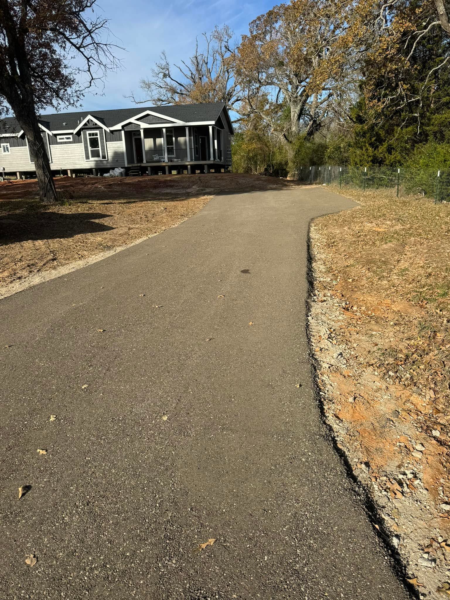 Curved gravel path leading to a house with autumn trees and fallen leaves on either side.