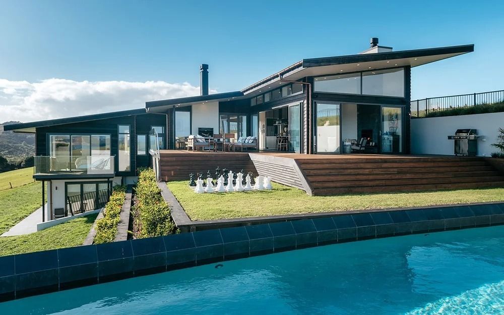 Modern house with a deck and pool beside a landscaped lawn under a bright sky - Waiheke Pure Rental