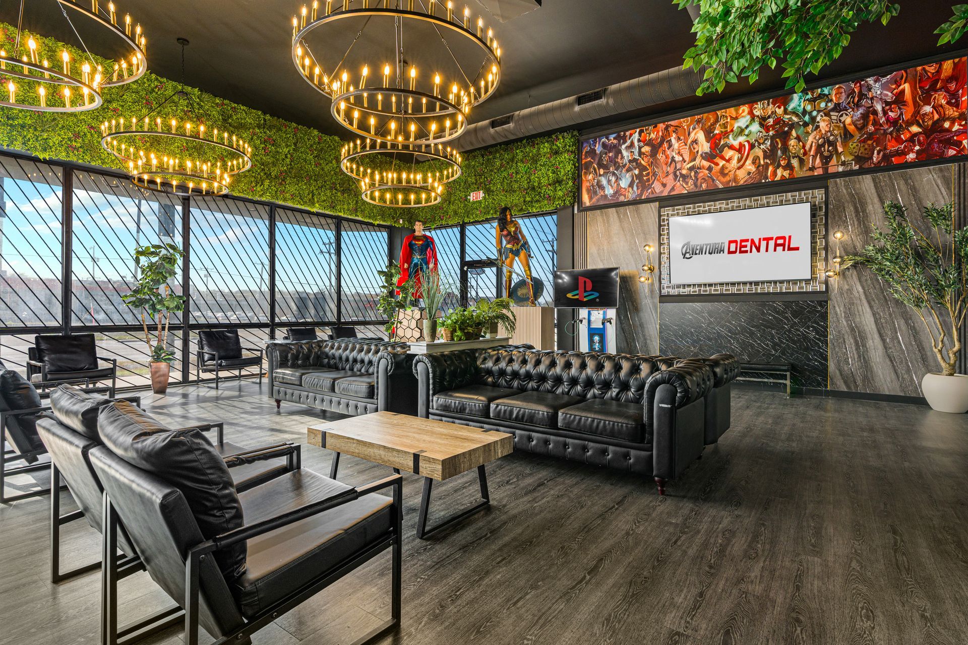 Stylish lounge with black leather seating, chandeliers, green wall accents, and a large wall-mounted screen