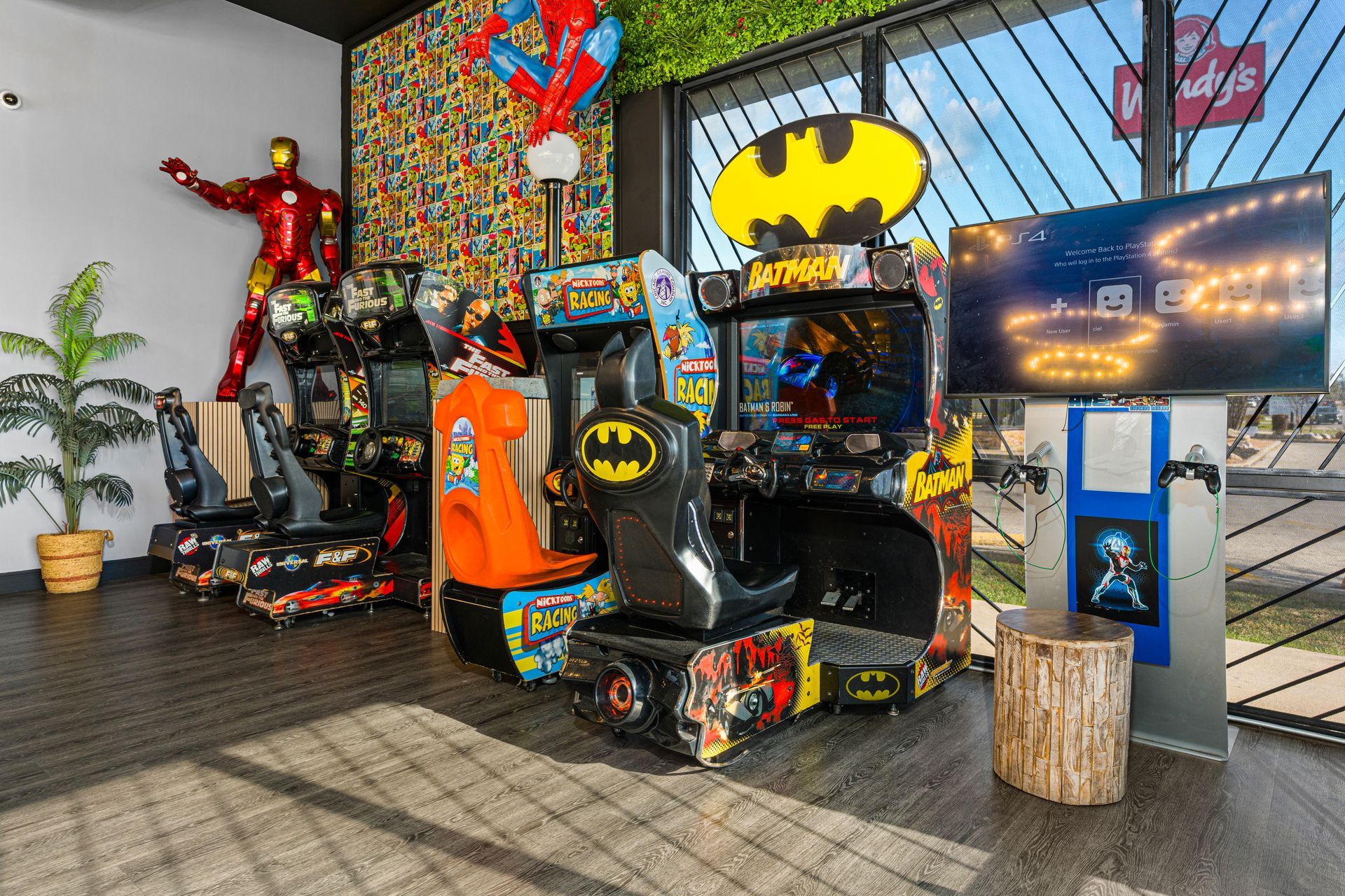 Batman-themed arcade corner with colorful racing game cabinets and a large Batman logo display