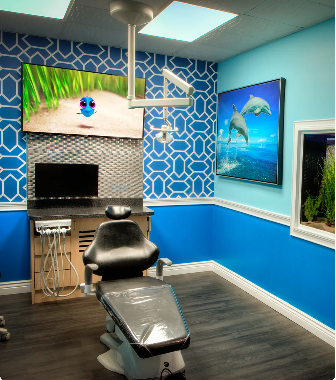 Modern dental exam room with blue walls, black chair, sink, and ocean-themed wall art