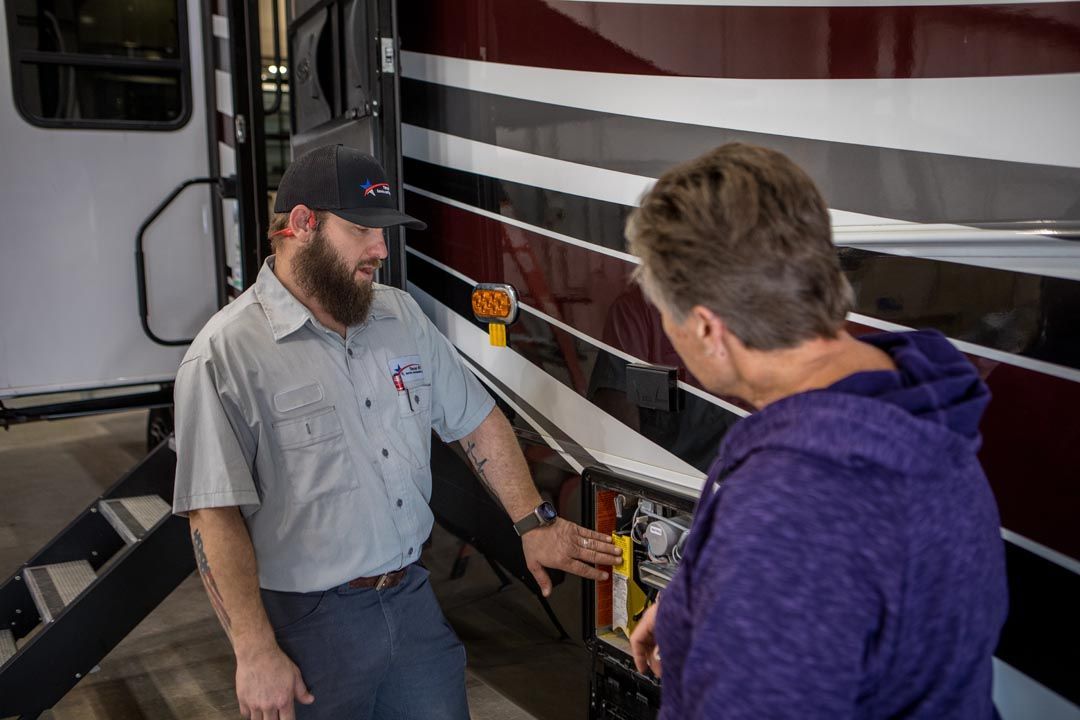Mechanic pointing to RV component, explaining to a customer.