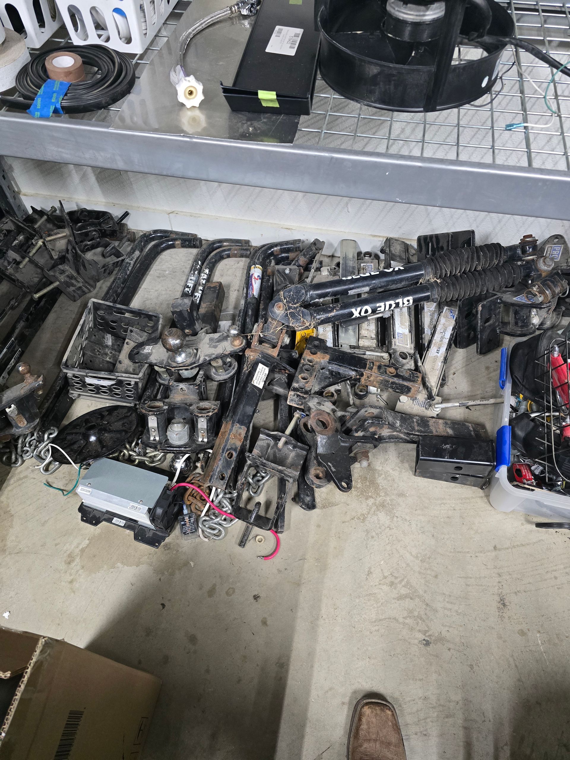 Assorted black mechanical parts laid out on a concrete floor in a workshop or garage.