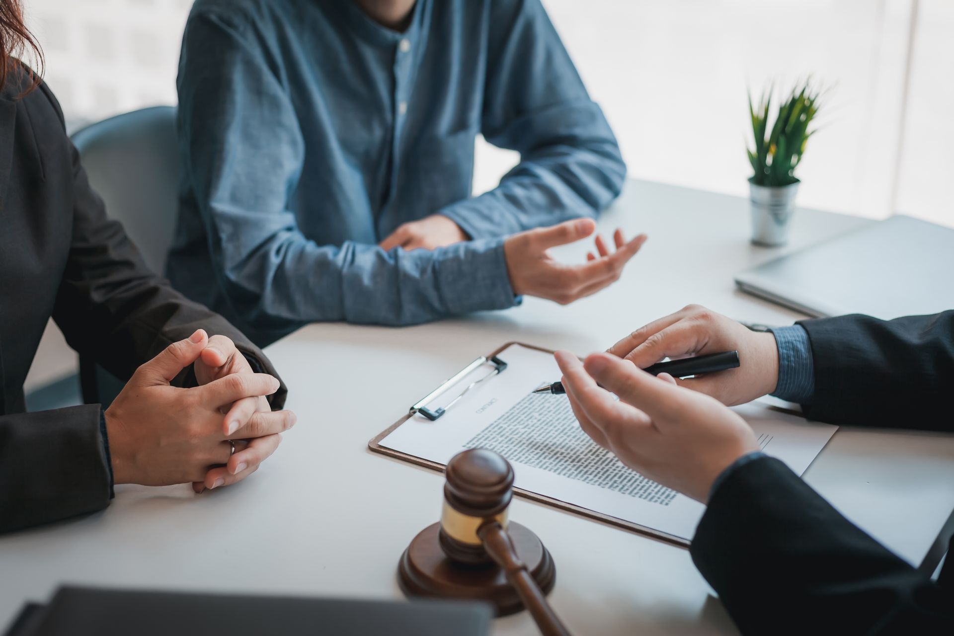 People meeting with a lawyer, discussing documents, gavel on table.