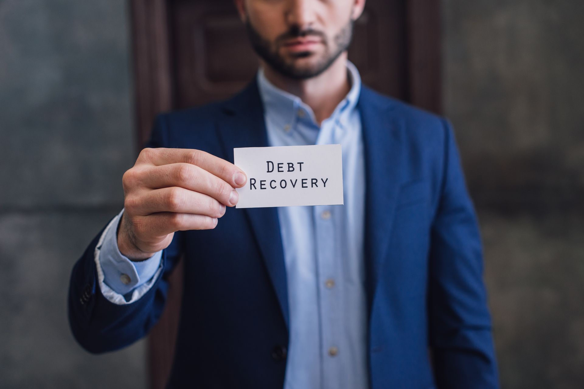 Man in blue suit holds a card that reads 