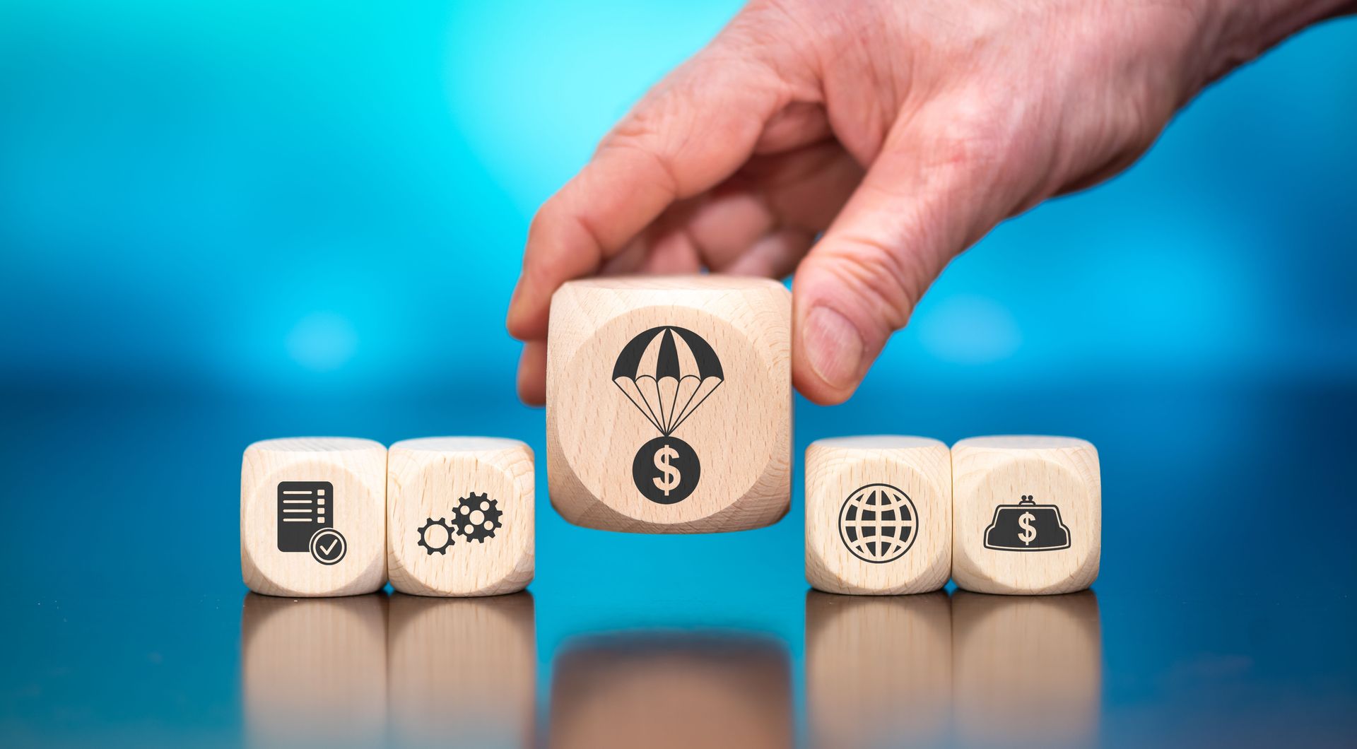 Hand placing a die with dollar sign and parachute symbol. 