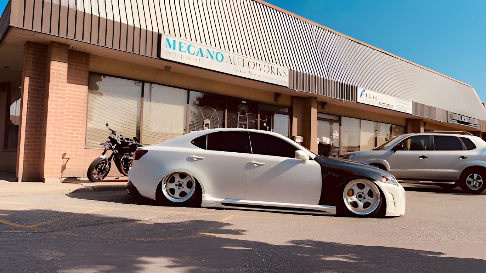 White and black modified Lexus sedan parked on the street in front of a building on a sunny day. | Mecano Autoworks