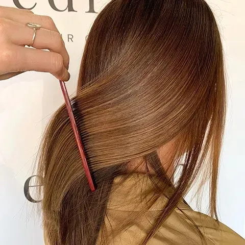 A Person's Brown Hair Being Combed with A Red Comb — EDISON Hair Collective In Mackay, QLD
