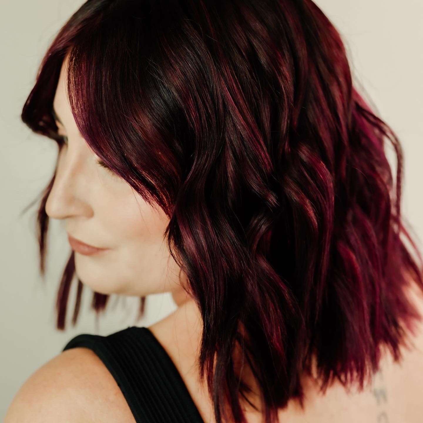 Woman with Short, Wavy Burgundy Hair, Looking to The Side, Wearing a Black Top — EDISON Hair Collective In Mackay, QLD
