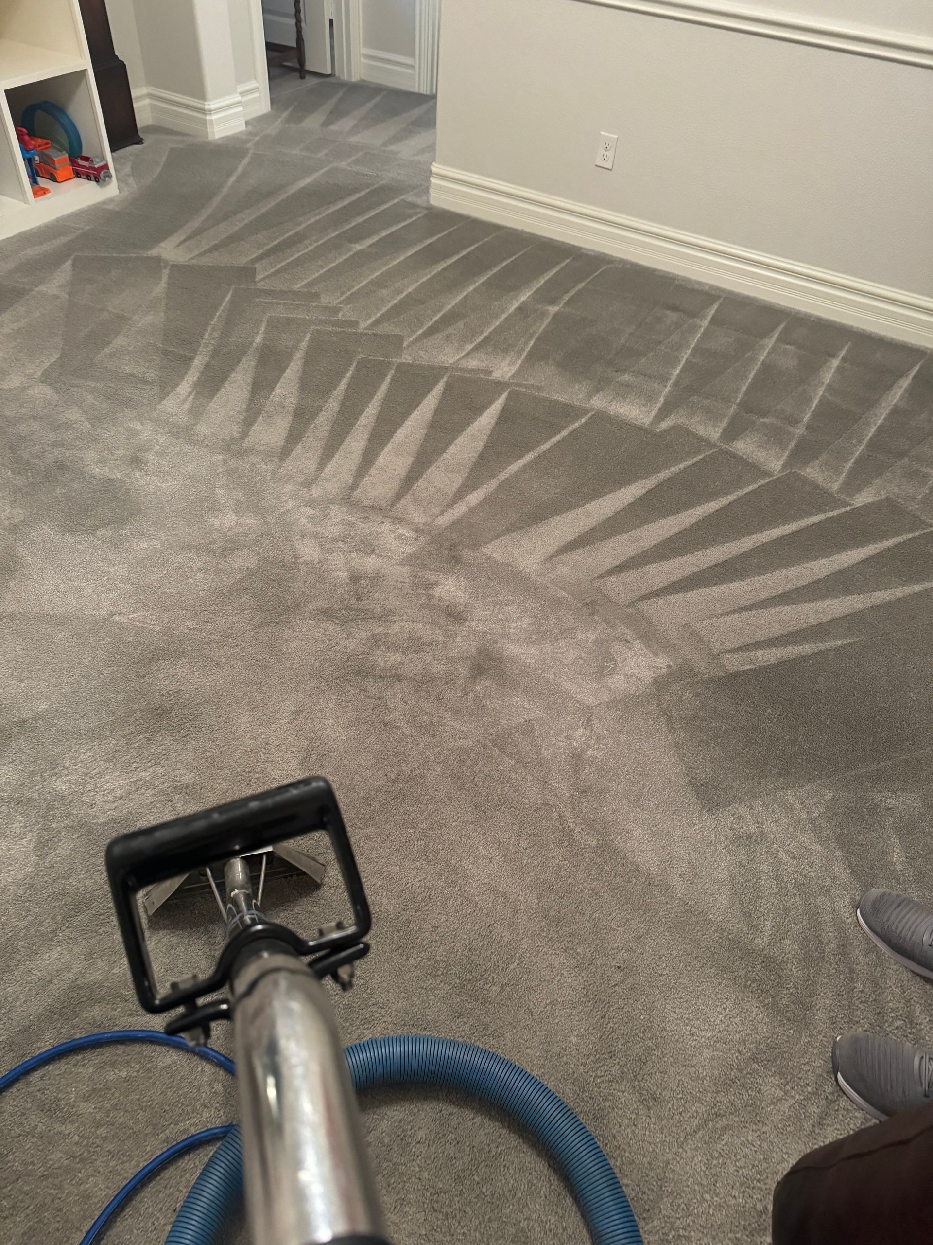 A vacuum cleaner is cleaning a carpet in a living room.