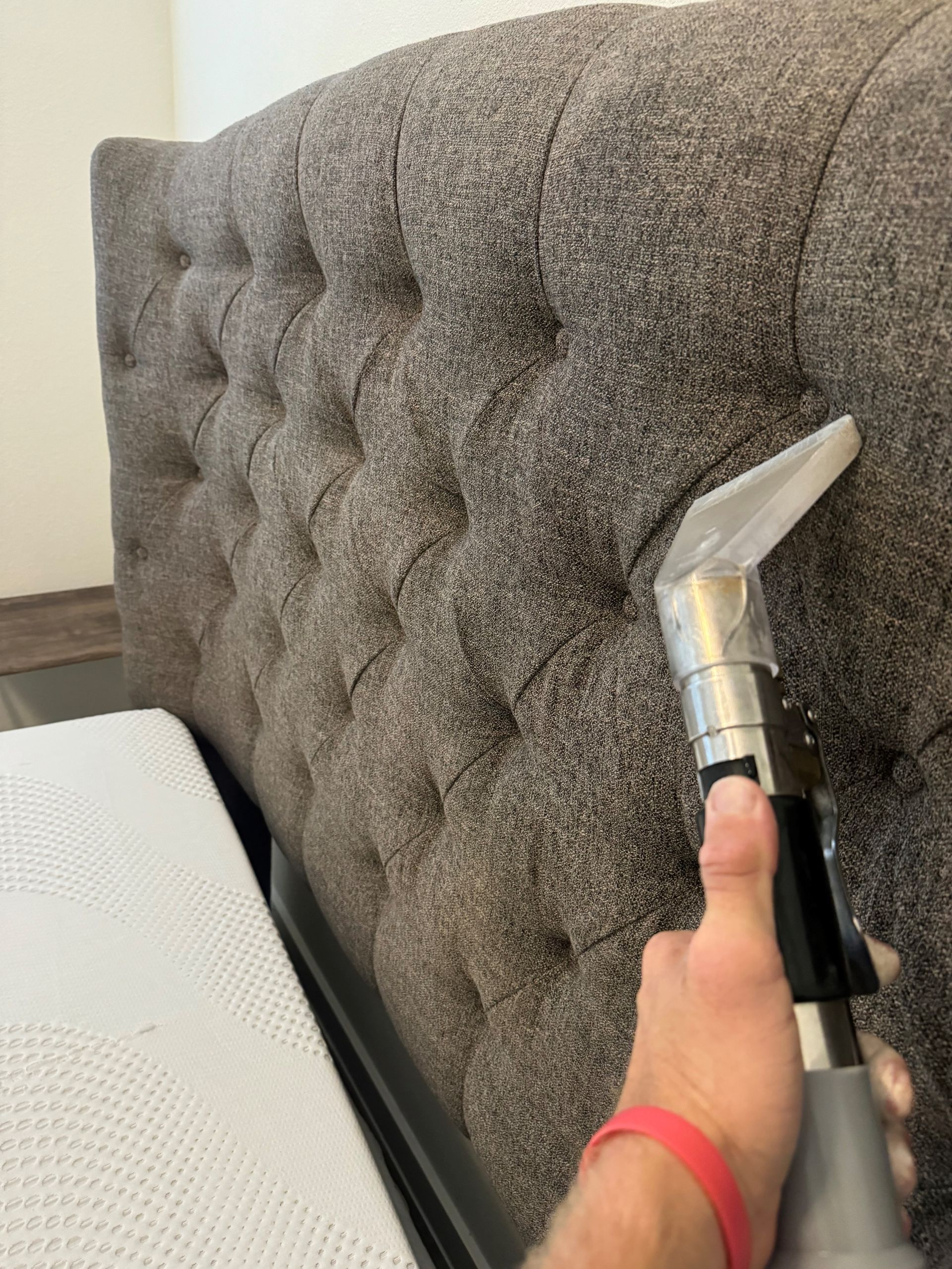 A person is cleaning a headboard with a vacuum cleaner.