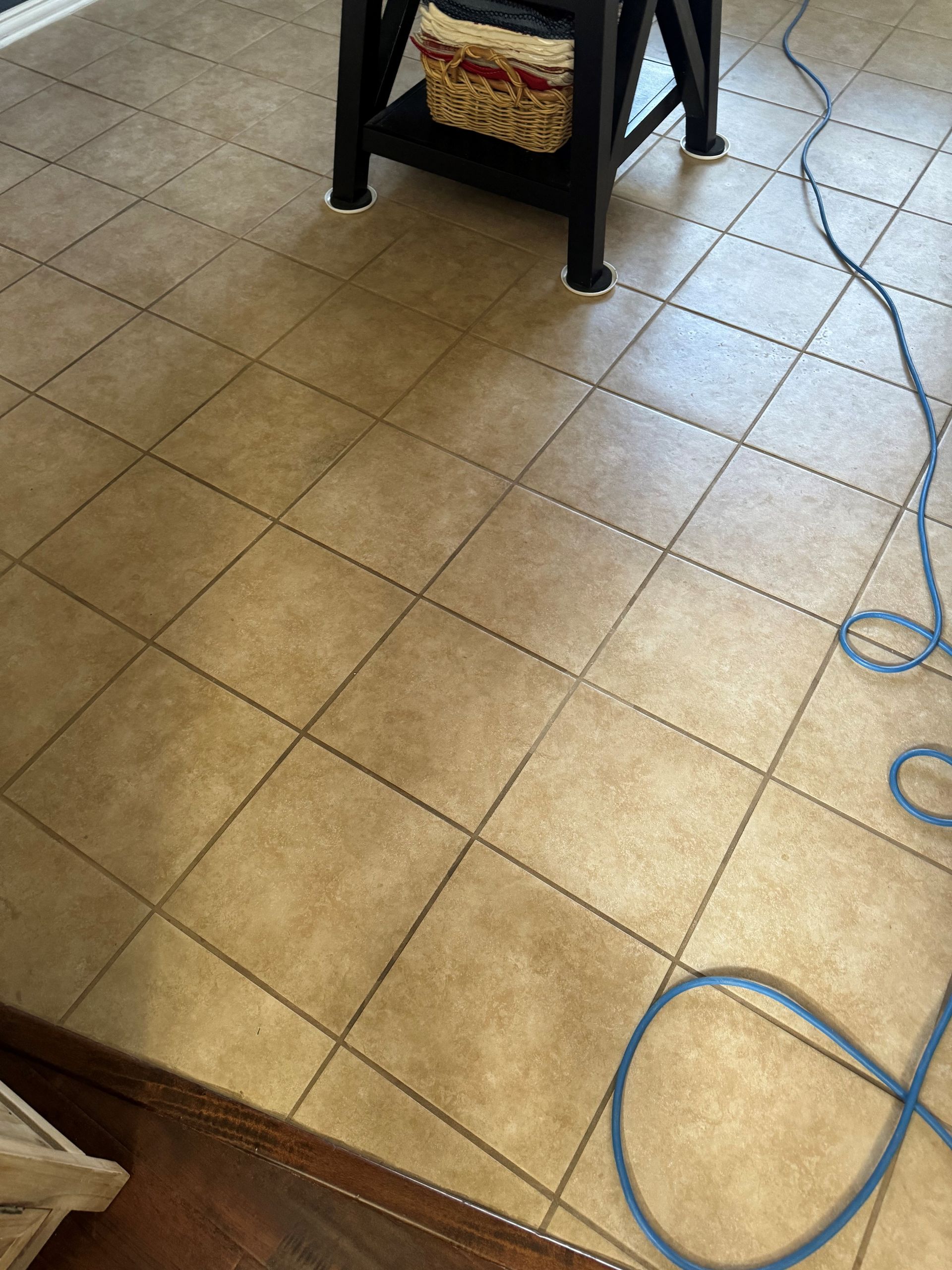 A person wearing yellow gloves is cleaning a white tile wall with a sponge.