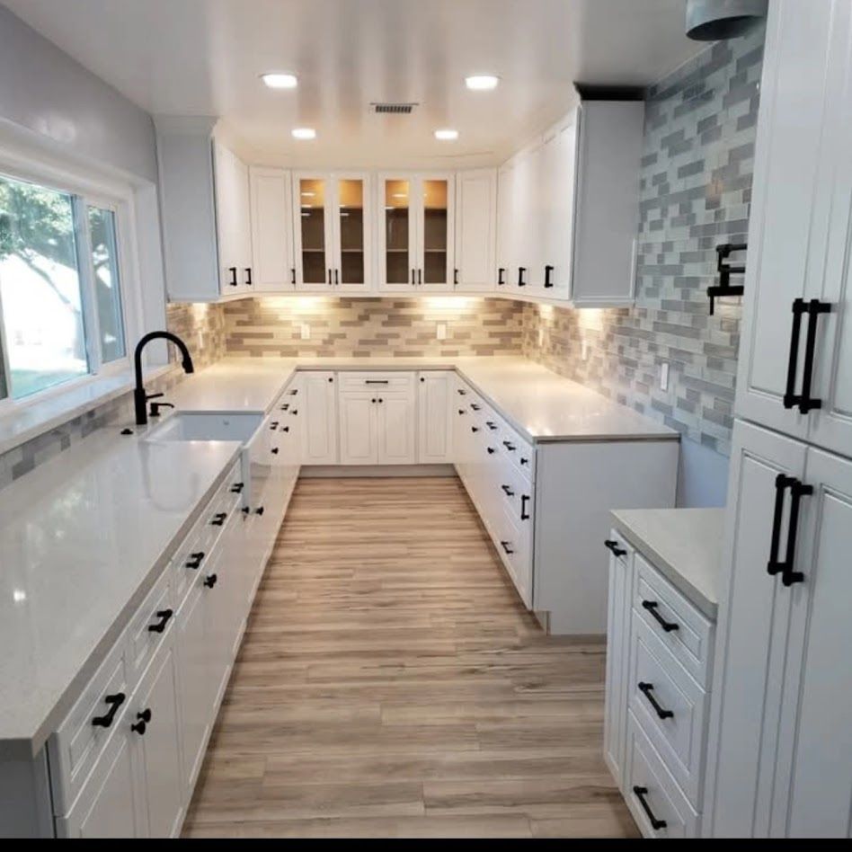 Bright modern white kitchen with island, light wood floor, marble backsplash, and large window