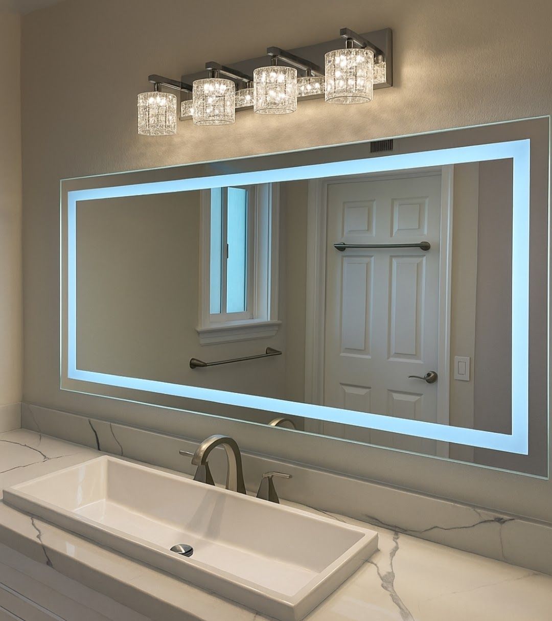 Bathroom vanity with lit backlit mirror, crystal light fixture, sink, and white door reflected in the mirror