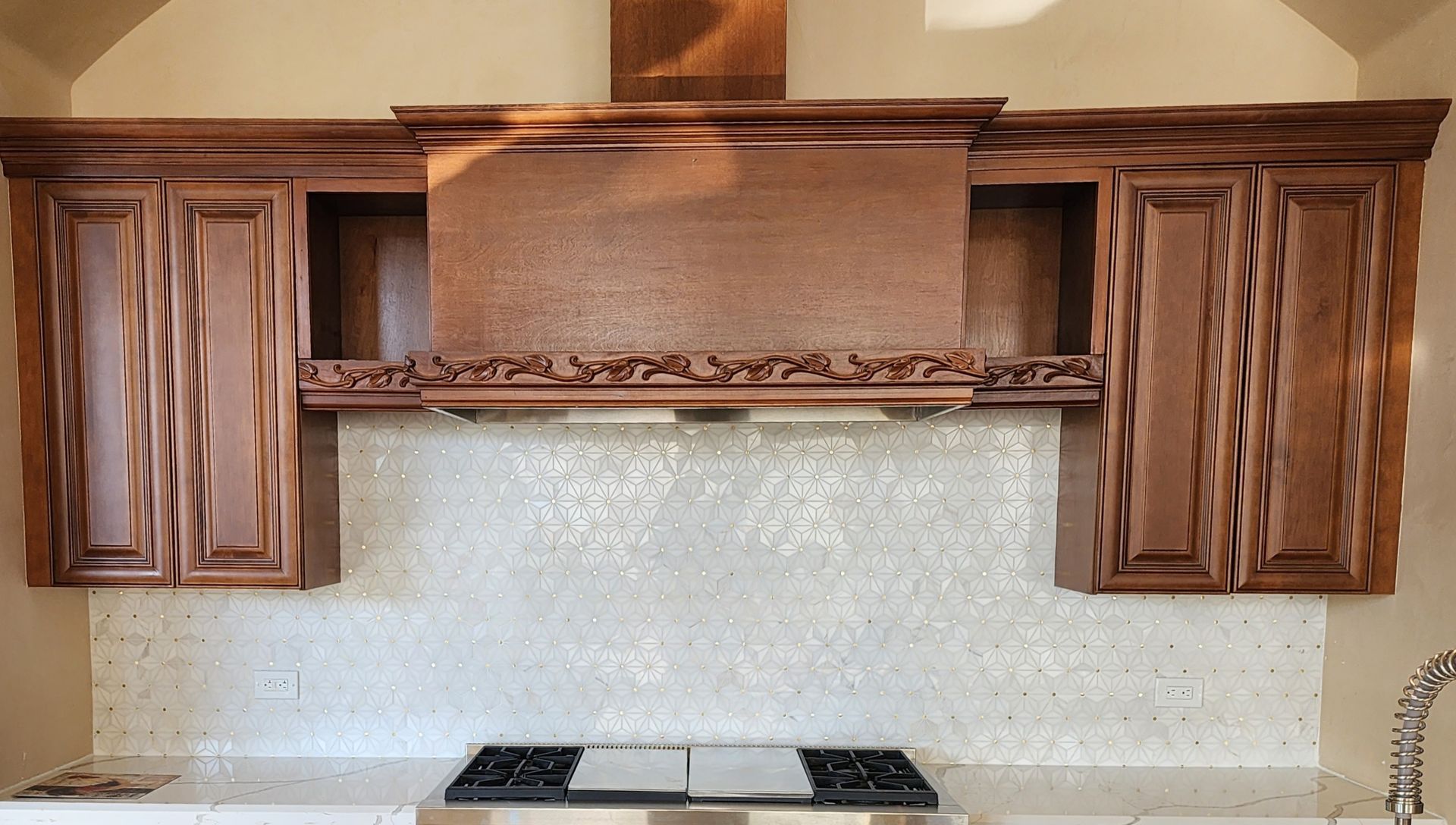 Kitchen range with dark wood cabinets, copper hood, and white backsplash above a stovetop