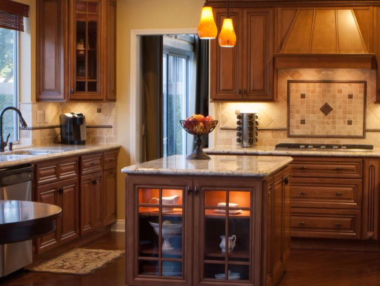 Warm wood kitchen with center island, pendant lights, and tiled backsplash in a modern home.