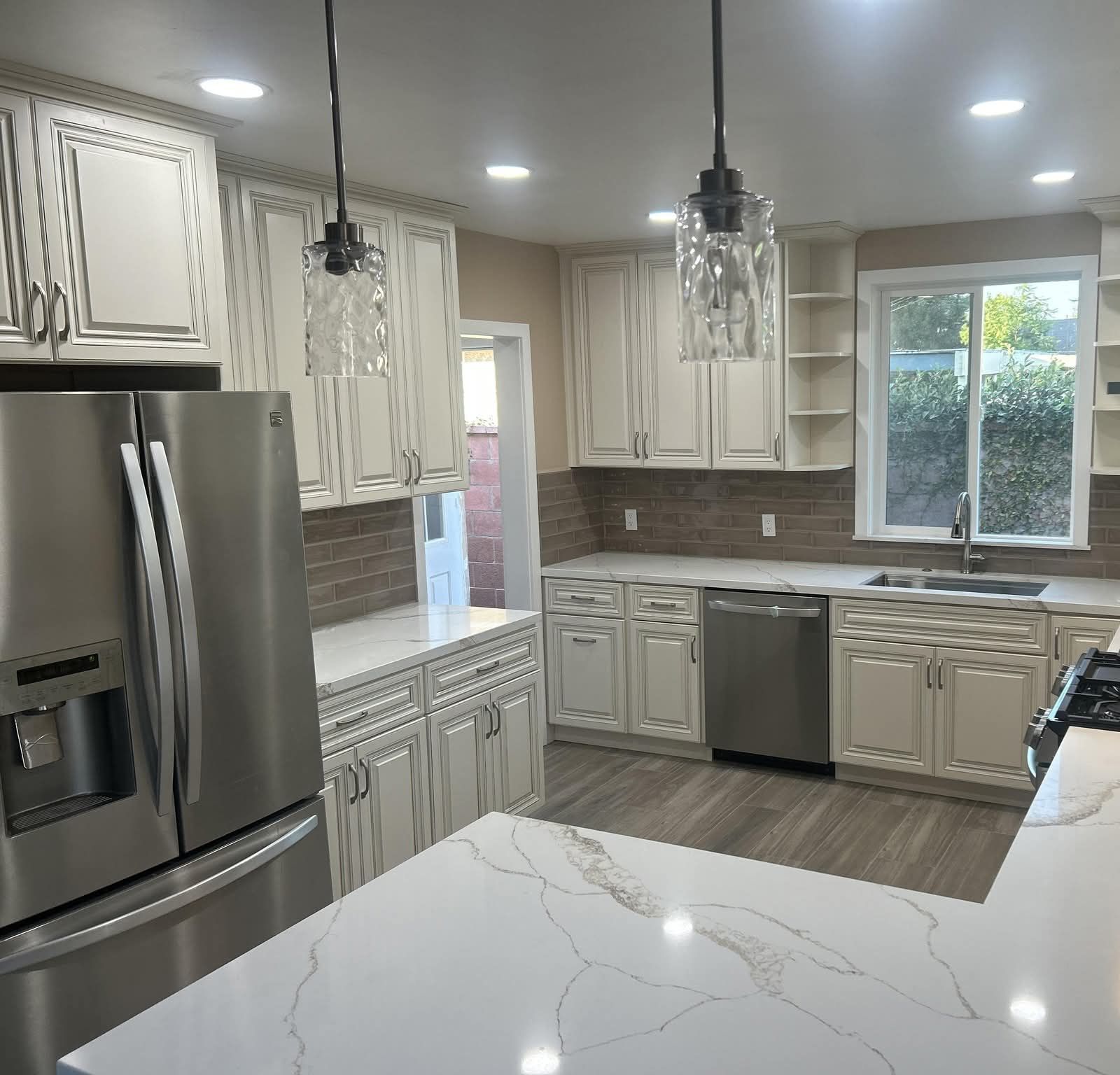 Bright modern kitchen with white cabinets, stainless steel appliances, and marble countertops