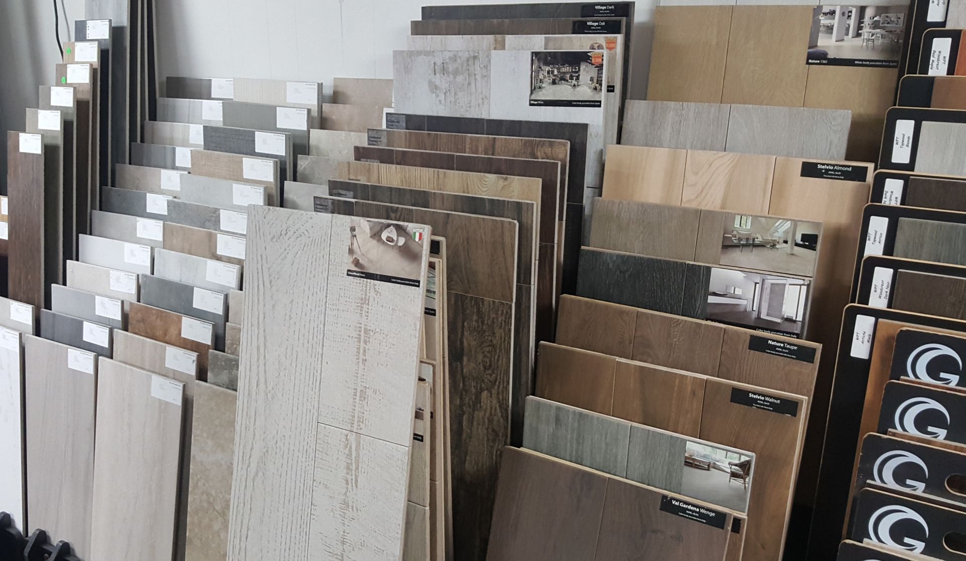 Display of stacked wood-look floor and wall tile samples in a showroom