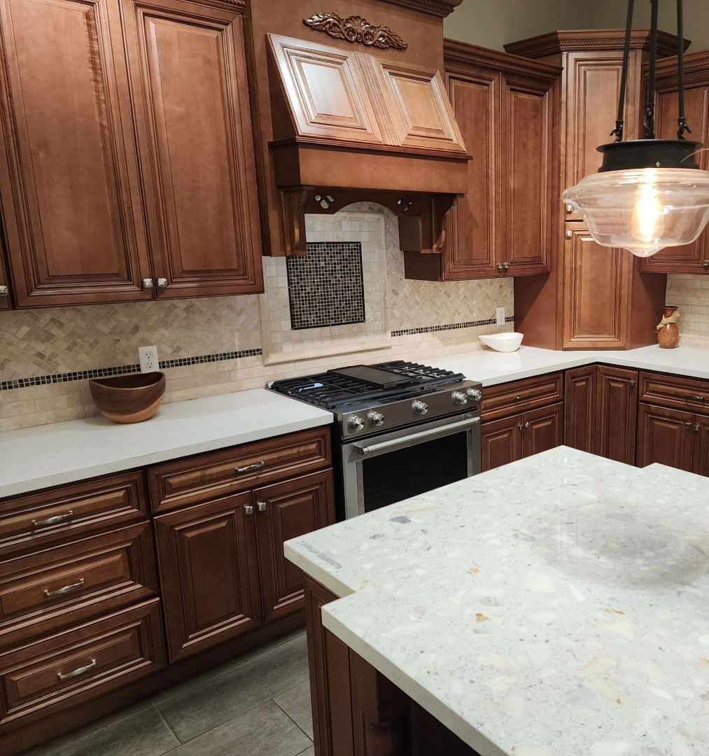 Warm wood kitchen with granite island, stainless stove, and decorative tile backsplash