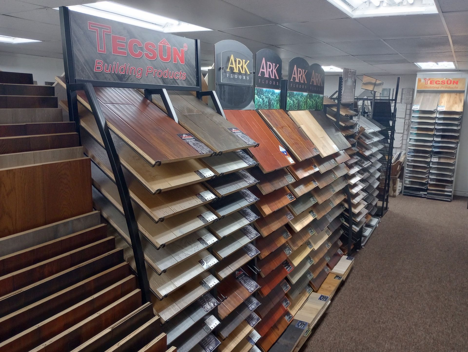 Flooring showroom aisle with rows of wood and laminate samples on display.