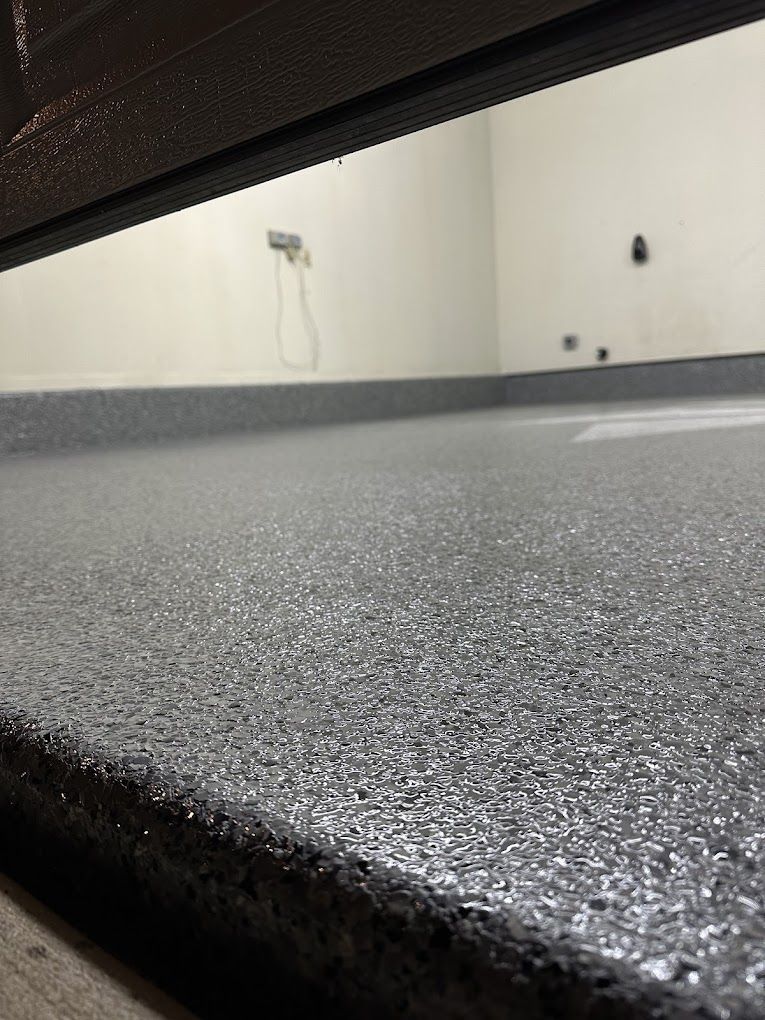 A close up of a gray floor with a white wall in the background