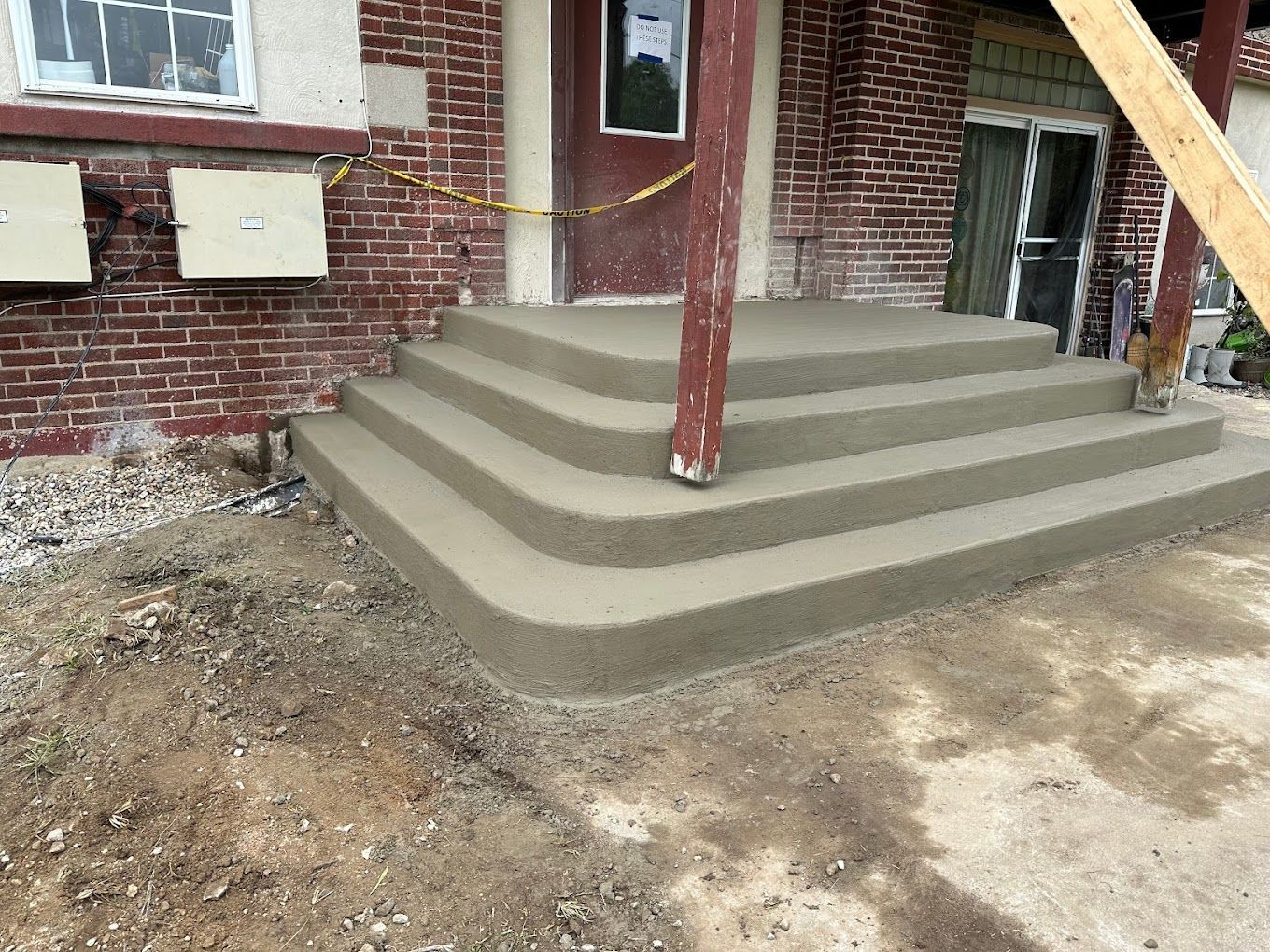 A set of concrete steps are being built in front of a brick building.