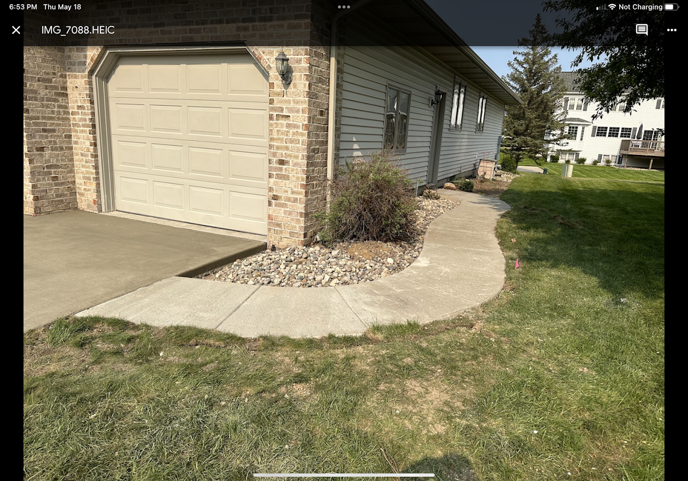 A picture of a house with a concrete walkway leading to it.