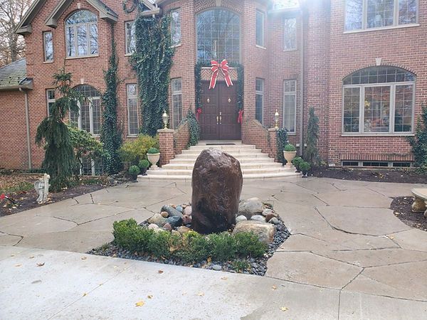 A large brick house with a fountain in front of it.